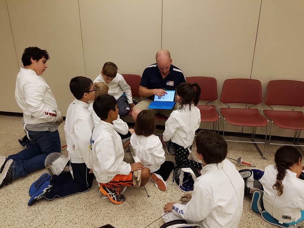 We were so caught up in the bouts we showed the kids that we forgot to take any pictures of the group watching the Olympic fencing. It basically looked like this picture, where Dan is showing the kids the pool sheet from their end-of-camp tournament.